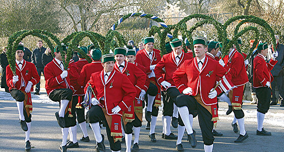 Traditionell gekleidet in roten Jacken, schwarzen Kniebundhosen und weißen Strümpfen  tanzen die  Männer den Schäfflertanz.