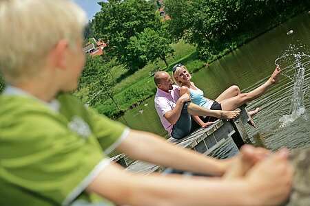 Vater, Mutter und Sohn vergnügen sich am sommerlichen Kurparweiher in Sankt Englmar.